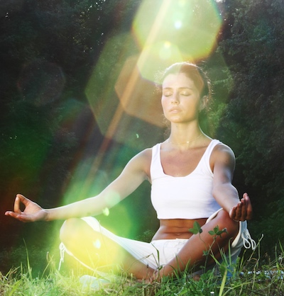 Woman meditating on grass.